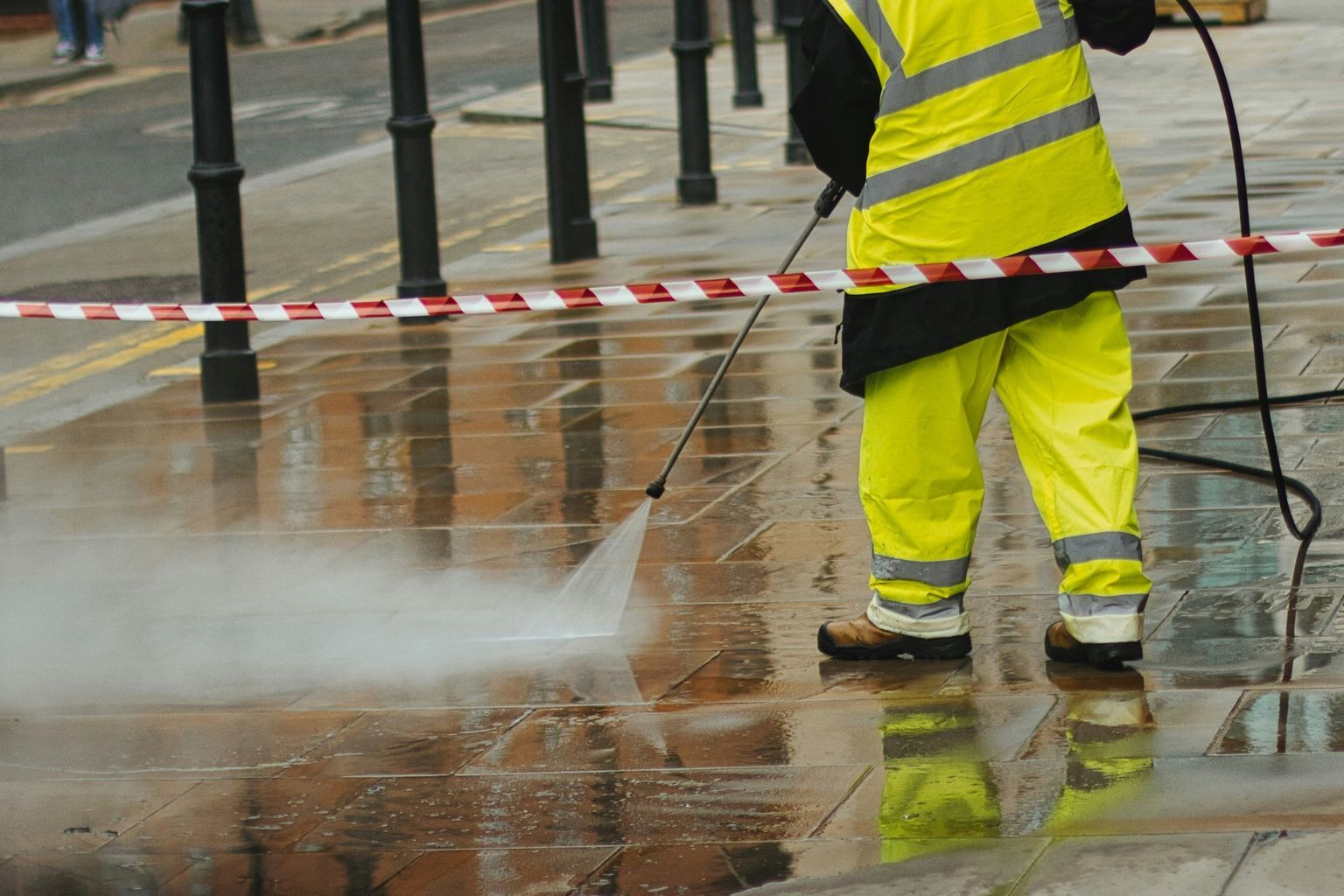 a man in a yellow jacket is using a pressure washer